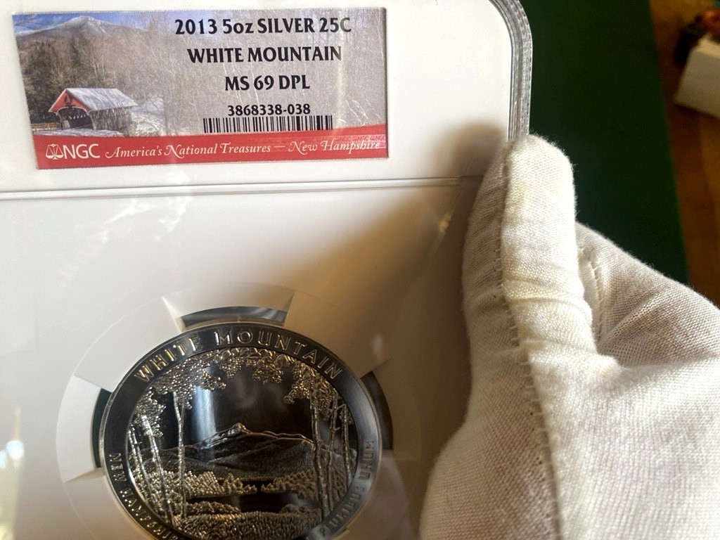 2013 White Mountain 5 oz Silver ATB — NGC MS69 DPL — obverse shown in hand, photographed in hand at Capstone Metals.