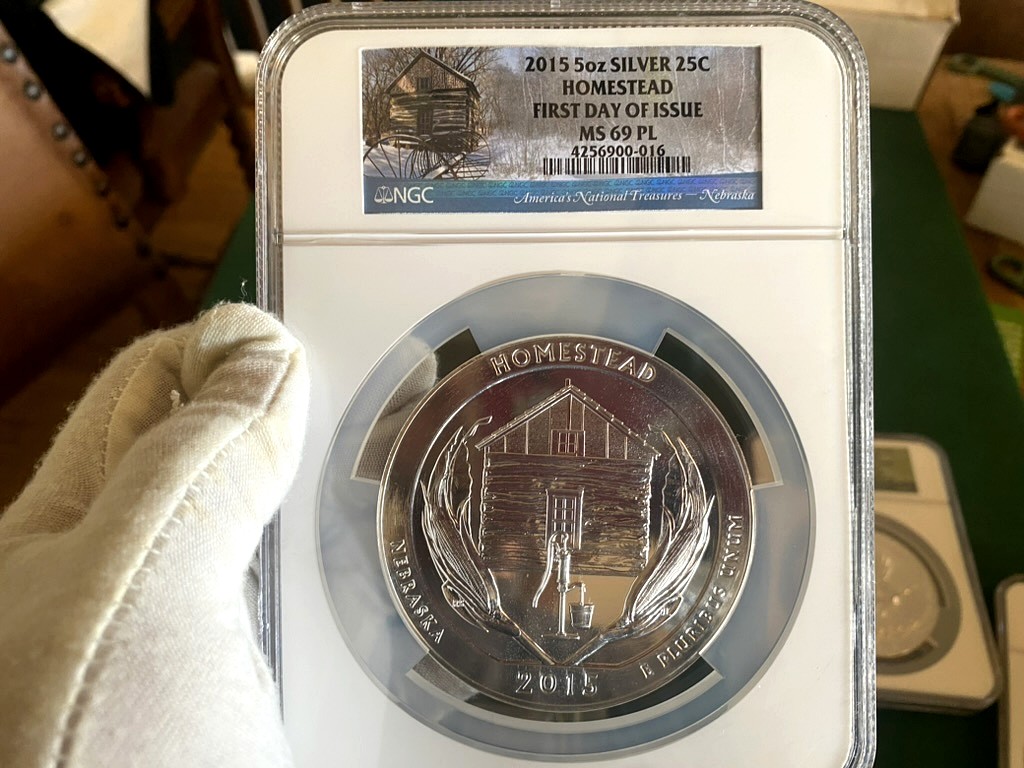2015 Homestead 5 oz Silver ATB — NGC MS69 PL First Day of Issue — obverse shown in hand, photographed in hand at Capstone Metals.